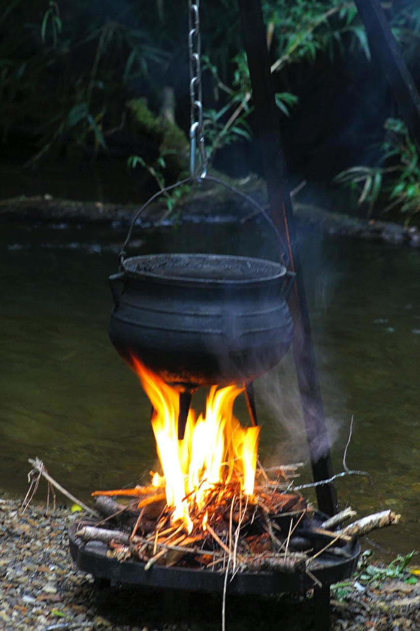 Olla de hierro sobre fogón de leña junto al río